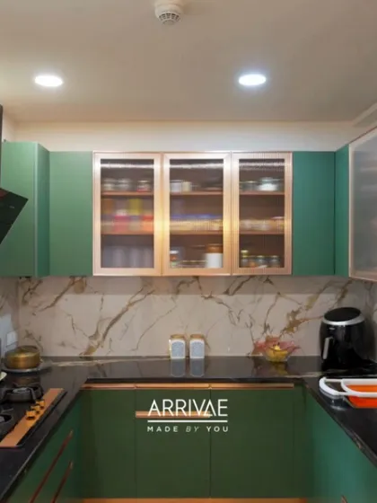 This U-shaped kitchen makes a bold statement with its rich green cabinetry and elegant rose gold accents. The design is perfectly balanced with a white marble-patterned backsplash and a dark quartz countertop, showcasing a luxurious yet functional space.