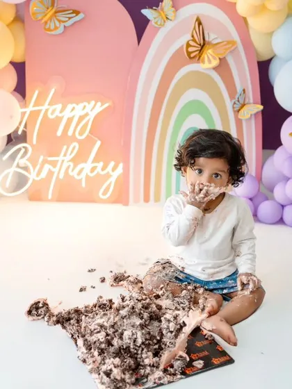 The cake smash is in full swing. This shot captures the messy, fun reality of a one-year-old's birthday celebration.