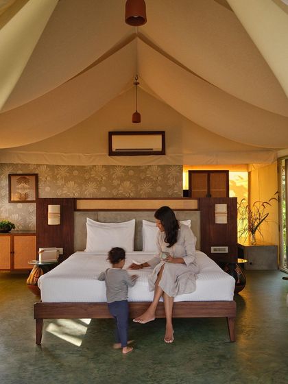 The interior of a glamping tent, where a canvas roof and natural materials create a cozy yet spacious atmosphere. The design combines the rustic appeal of camping with the comforts of a luxury resort room, complete with views of the outdoors.