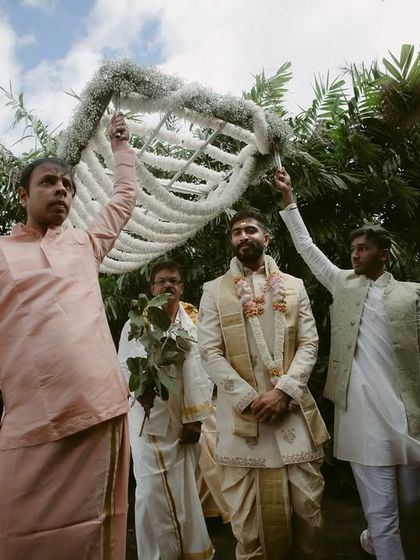 The groom's procession, where he is escorted under a decorative canopy by his family. A moment of tradition and community.