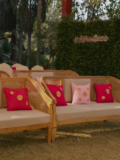 Chic and comfortable seating for a daytime Haldi event. The cane furniture is accented with bright pink cushions, adding a pop of color that complements the festive atmosphere.