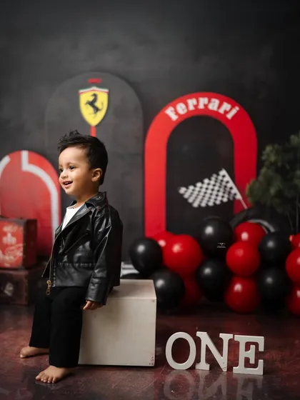 A candid moment of laughter during the Ferrari-themed first birthday session. The red and black color scheme creates a bold and exciting backdrop.