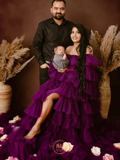 A stunning family portrait with new parents and their baby. The mother's dramatic purple gown adds a touch of glamour to this special moment.
