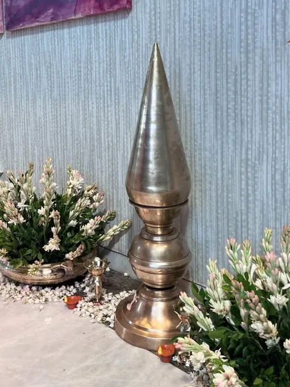A close-up of a traditional brass finial and fresh white flowers. These details add a sense of sacredness and elegance to an engagement ceremony.