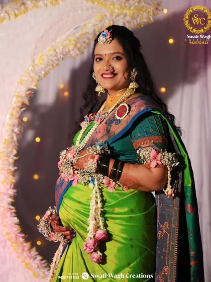 The happiness of being a mother, captured perfectly. This client is wearing a beautiful set with pink roses and a custom 'Aai' brooch.