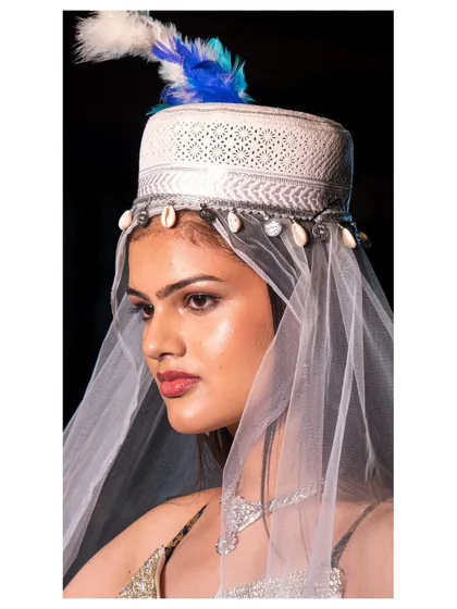 A detailed close-up of a model wearing a traditional-style headpiece with shells and a veil. We excel at capturing intricate accessories and makeup details that complete a designer's runway look.
