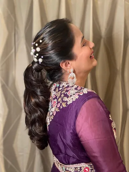A side view of the pearled ponytail, showing the happy client and the beautiful volume in her hair.