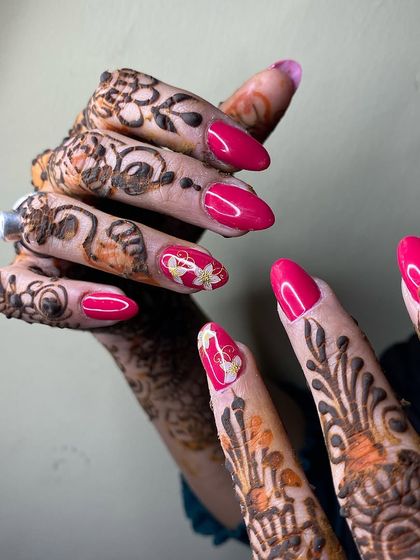 A vibrant pink nail set with gold chrome accents, perfectly complementing the intricate henna design for a wedding or festive occasion.