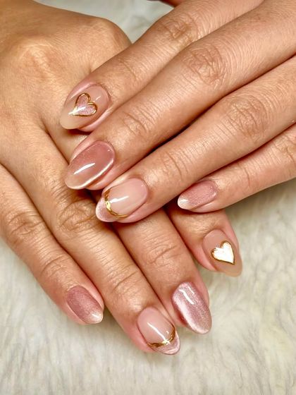 Fall in love with your nails, literally. This dreamy pink cat-eye set is paired with delicate gold heart outlines for a look that is both trendy and romantic.