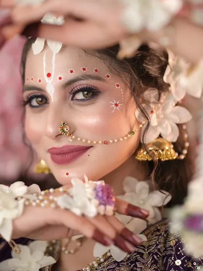 A captivating close-up of the Radha makeup, showing the intricate white and red dot work and the glowing skin finish.