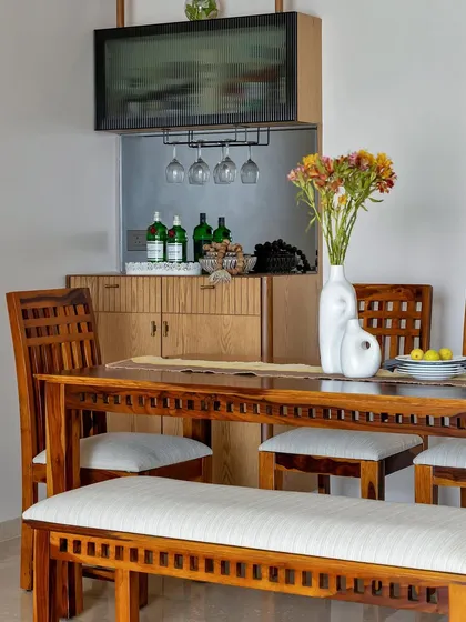 This setup shows how a dining area can be perfectly integrated with a home bar. The warm wooden dining set is complemented by a functional and stylish bar cabinet, ready for any occasion.