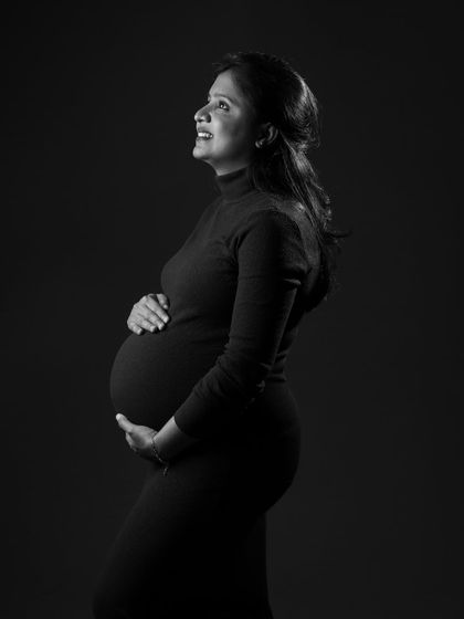 A beautiful and hopeful black and white portrait. The mom-to-be looks up with a gentle smile, and the dramatic lighting creates a feeling of strength and anticipation.