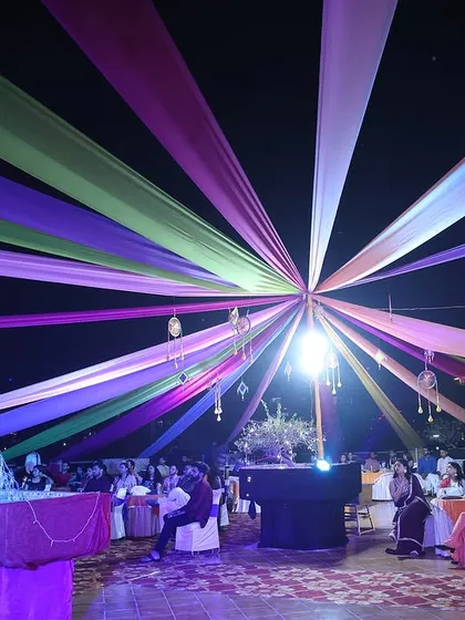 Creating the perfect ambiance for an evening event. This rooftop setup features a vibrant canopy of draped fabrics and hanging decor, transforming the space for a corporate celebration under the stars.