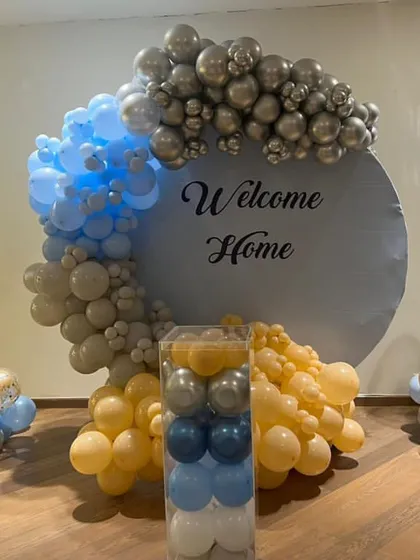 A charming "Welcome Home" backdrop in blue, yellow, and silver. This teddy bear themed setup includes a circular backdrop and two balloon stands with cute teddy bears, ideal for a party or home corner.