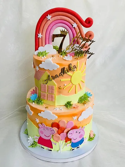 A two-tier Peppa Pig cake with a warm, sunset-orange color palette. This design features Peppa and George with balloons under a big rainbow, ready for a party.