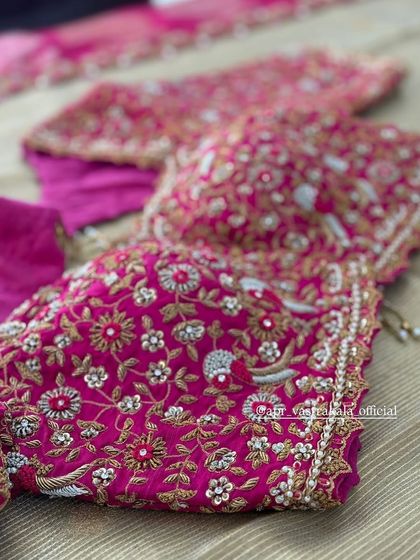 A close-up of the dense floral embroidery on the pink blouse.