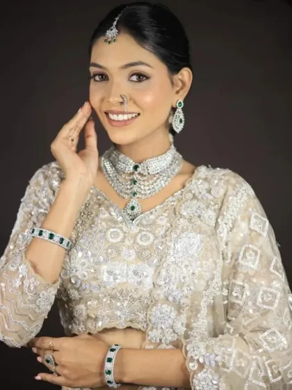 A smiling client showing off the emerald jewellery set that she rented along with the white lehenga.