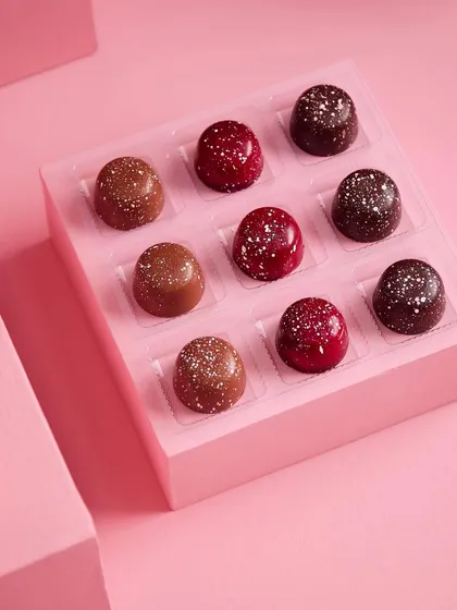 A close-up of our handcrafted Belgian truffles. Each piece is a bite of pure indulgence, with flavours like rich dark chocolate and sweet raspberry, finished with a delicate dusting of cocoa.
