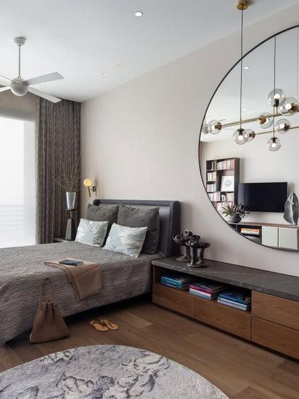 A full view of the guest bedroom, showcasing its thoughtful layout. The large circular mirror is a key design element, reflecting light and the room's sculptural details, making the space feel larger and more dynamic.