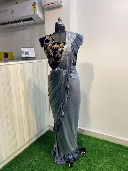 For a look that is both glamorous and effortless, I offer this ready-to-wear ruffled saree. It combines a rich, dark blue velvet blouse with floral embroidery and a pre-draped silver-grey ruffled saree, so you get a perfect drape every time.