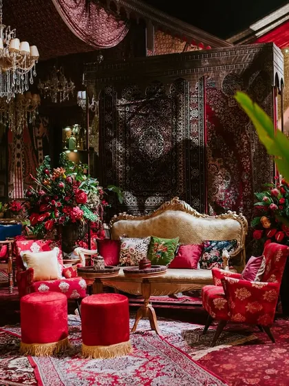 A view through the lush foliage shows a comfortable and opulent seating area. The mix of vintage furniture, rich textiles, and abundant florals is central to my design philosophy of creating layered, immersive worlds.