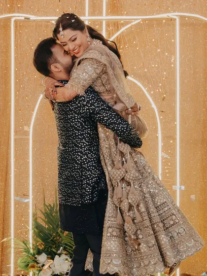 A joyful moment as the groom lifts the bride in a happy embrace during their engagement celebration.