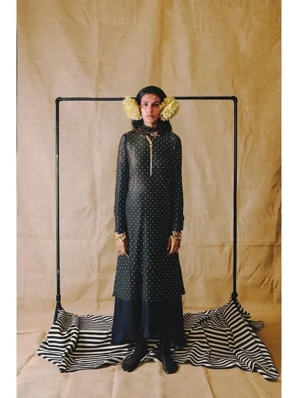 A full-length shot from 'Neo-Boheme'. The styling uses a simple frame to create a 'picture within a picture', highlighting the layered polka-dot look and floral headpiece.