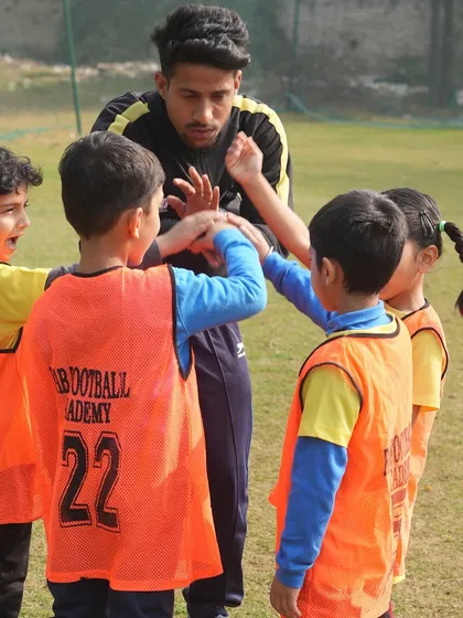 A coach with his hands on the players' hands. We teach teamwork and collaboration from the very beginning.