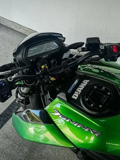 A top-down view of the cockpit of "Diana," a green Dominar, showing the handlebars and instrument cluster. This is the rider's office.