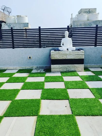 A checkerboard pattern of stone and artificial grass adds a playful touch to this terrace, which also features a Buddha statue on a stone podium.