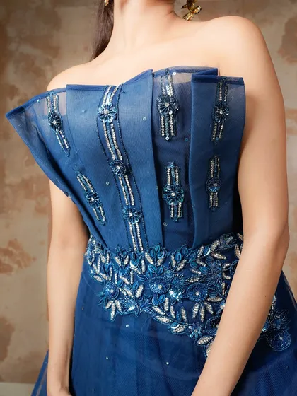 A detailed close-up of the blue gown's corset bodice. This shot highlights the intricate beadwork, the structured boning, and the unique texture of the fabric, showcasing the designer's craftsmanship.