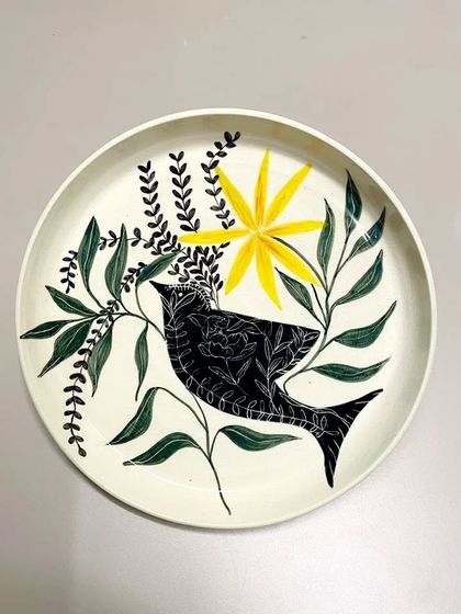 This sold plate is a vibrant example of my hand-painted work, featuring a bird surrounded by lush foliage and a bright yellow flower. It's a piece designed to bring joy and color to any space.