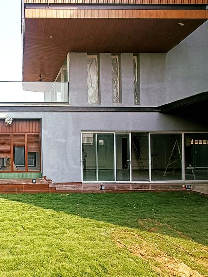 A view of the Lakewood Residence's garden-facing facade, showing the seamless connection between the indoor living spaces and the outdoor lawn through large sliding glass doors.