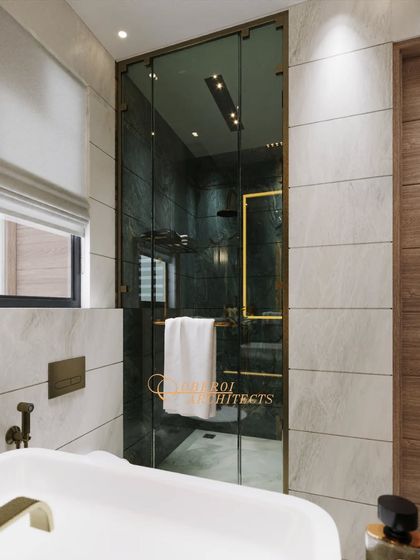 A detail shot of a bathroom where deep green marble textures and a glass shower door with brass fittings come together to define sophistication.