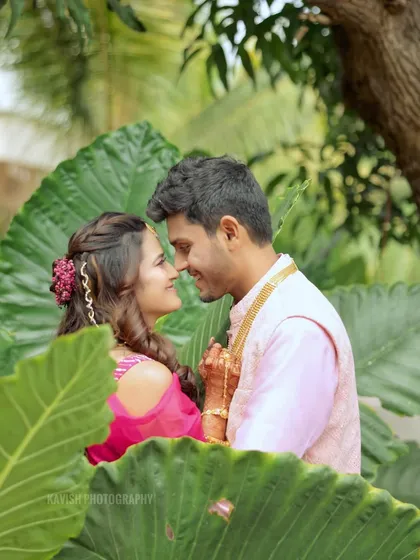 A romantic and candid moment between the wedding couple, captured through a frame of leaves.
