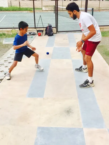 A young athlete lunges to catch the reaction ball. This type of off court training is crucial for developing the first step quickness needed to reach tough shots.
