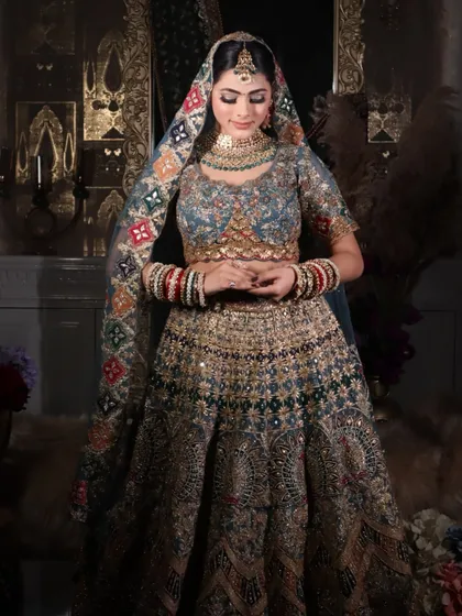A standing portrait of the bride, showcasing the unique, colorful dupatta and the elegant makeup.