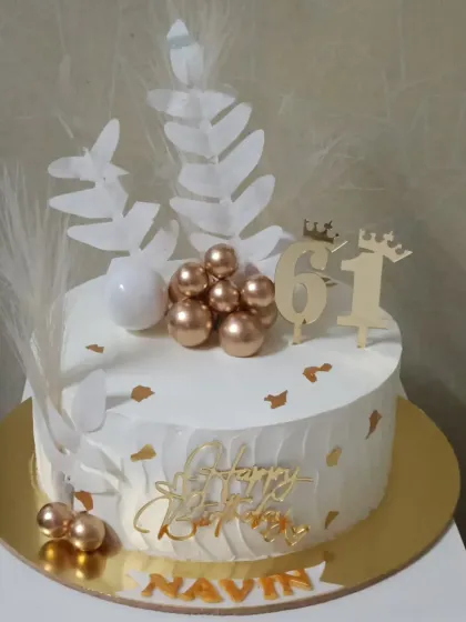 This 61st birthday cake has a modern, artistic feel with white wafer paper leaves, pampas grass accents, and a cluster of gold spheres. It’s a chic design for a stylish celebration.