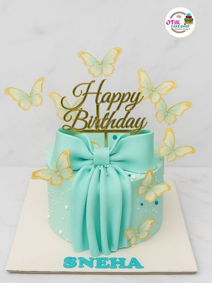 A dreamy aqua-colored cake adorned with a large fondant bow and delicate wafer-paper butterflies. This design is perfect for someone who loves whimsical and elegant styles.