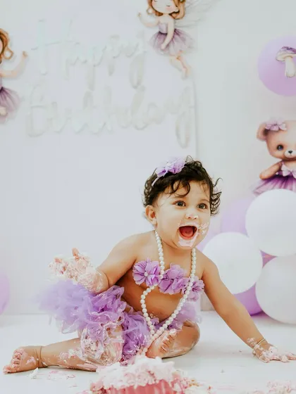 A wide-eyed look of delight. The combination of the purple tutu, pearls, and cake makes for a truly memorable first birthday portrait.