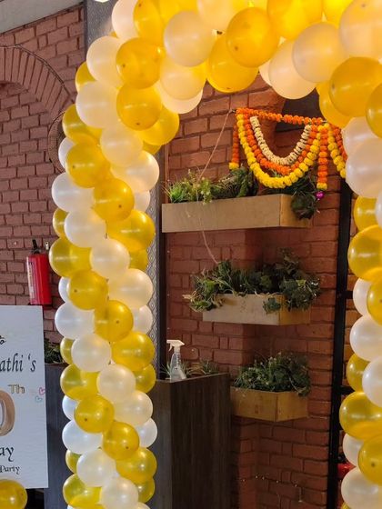 The entrance to the 60th birthday and retirement party, featuring a yellow and white balloon arch and a welcome sign that sets the tone for the event.