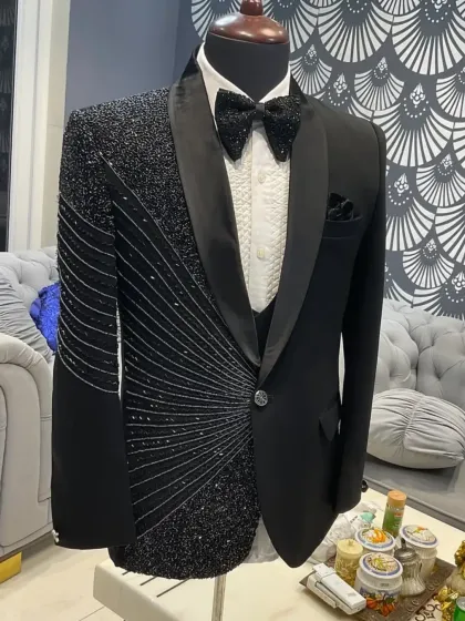This black tuxedo features an asymmetrical design with one side heavily embellished with radiating lines of black crystals. It's a modern, artistic take on the classic groom's tuxedo.