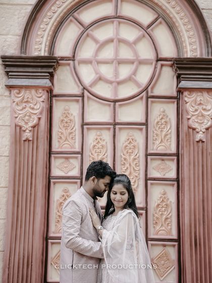 An intimate portrait of a couple in traditional attire, standing before a grand, ornately carved door.