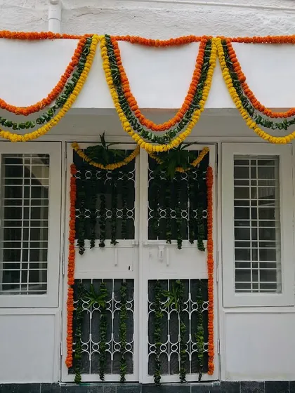 A simple and elegant door decoration for a house, using multi-colored marigold garlands to create a beautiful arch.