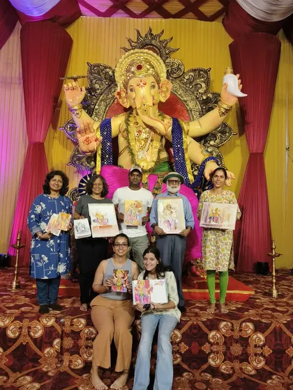 Our group of artists from Suburban Sketchers Mumbai posing with our artwork in front of the magnificent Ganpati idol. Sketching together during the festival is a cherished tradition.