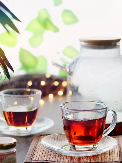 A still shot of two glass cups filled with tea, with soft, warm lighting in the background to create a relaxing and cozy mood.