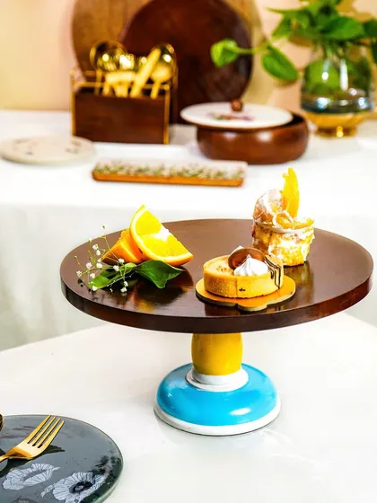 A full view of a styled table scene, showcasing a cake stand with pastries in a lifestyle context.