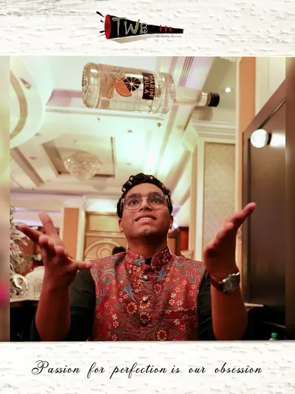 A flair bartender tosses a bottle, entertaining guests while preparing their drinks.