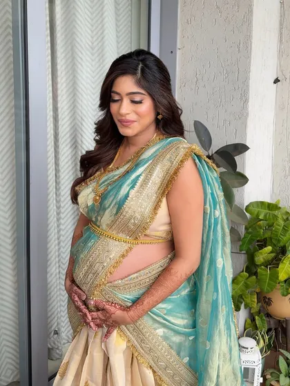 The half-up style with flowing waves beautifully complements the traditional saree, creating a look of serene elegance for this baby shower.