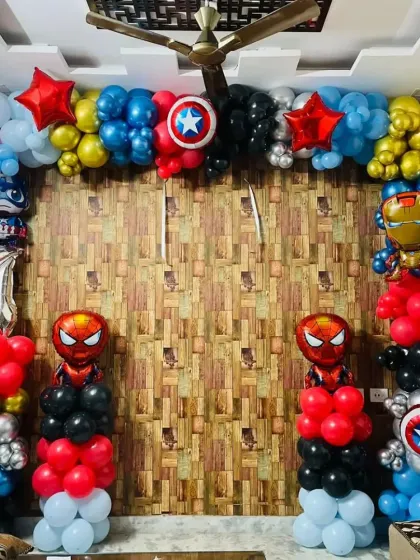 An action-packed Avengers theme birthday for a young superhero fan. The setup includes a full balloon frame with character foils of Iron Man, Captain America, and Spider-Man, set against a wood-paneled wall for a dynamic look.